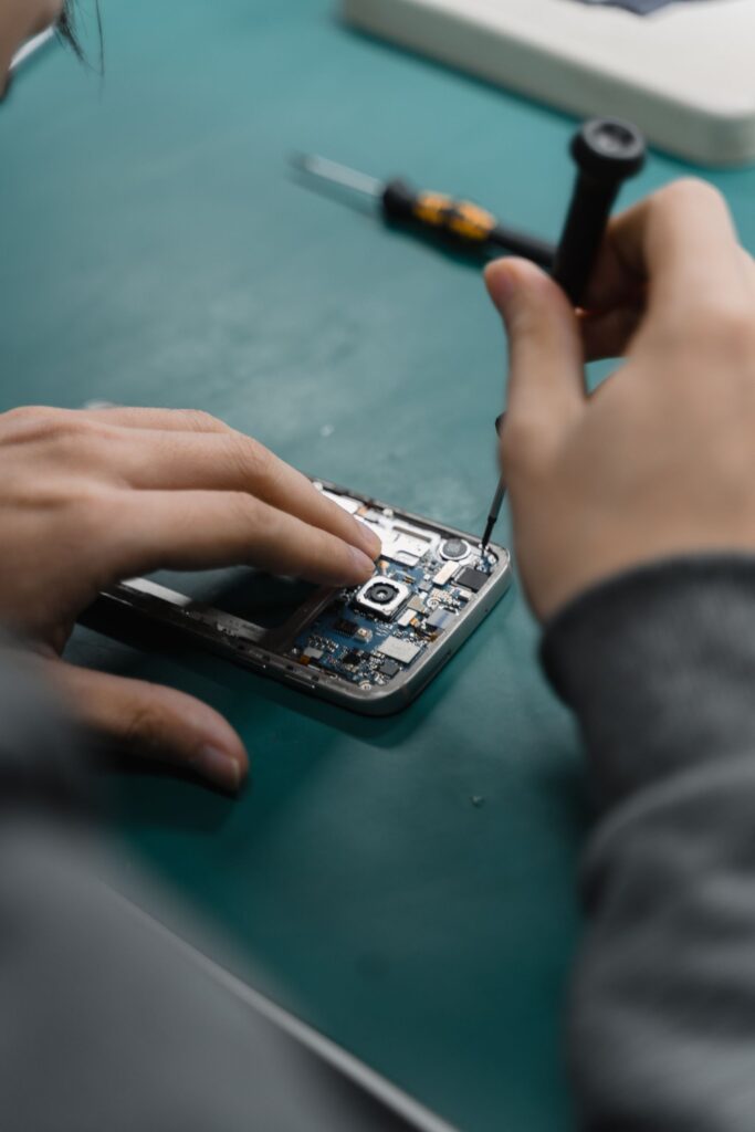 現在の画像: A focused view of repairing a smartphone circuit board with tools by hand.
