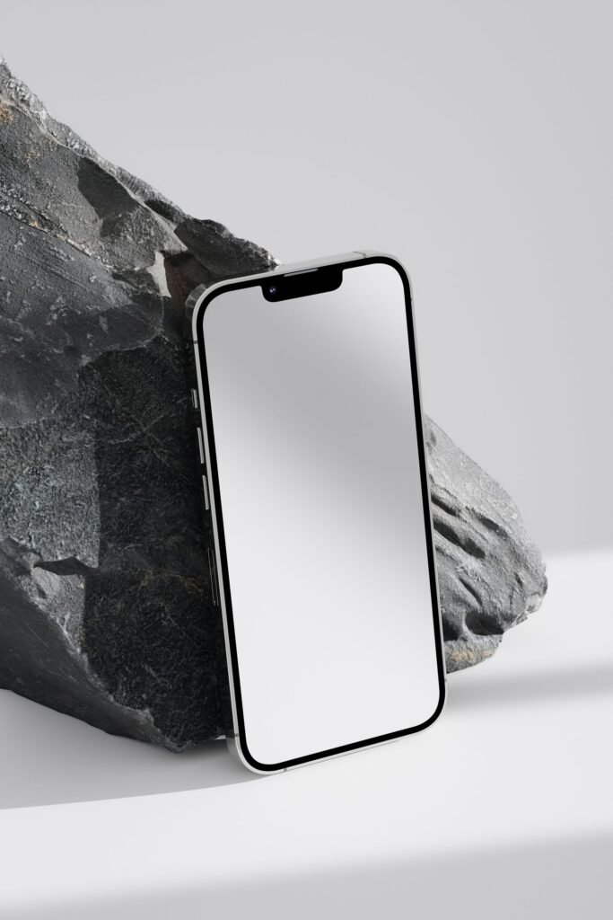 現在の画像: Close-up of a smartphone against a stone background, emphasizing modern design.