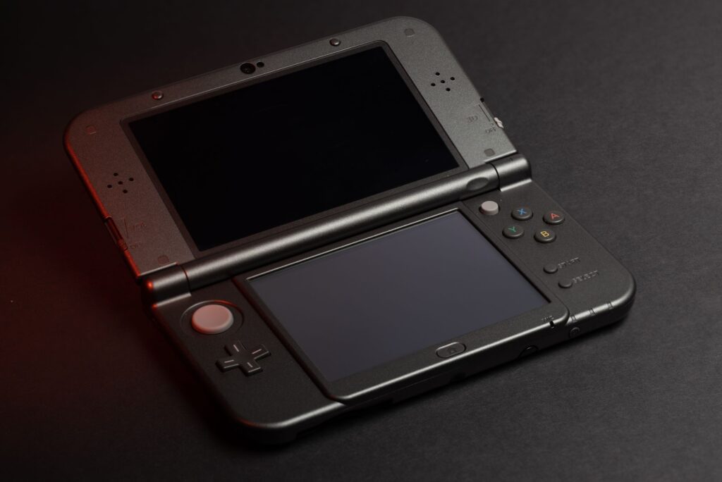 現在の画像: Detailed photo of a Nintendo 3DS console with dual screens and buttons, perfect for gaming enthusiasts.