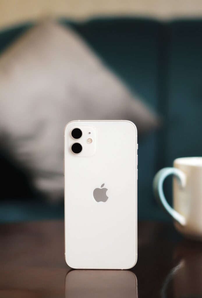 現在の画像: Elegantly designed smartphone standing on a wooden table with a soft blurred background, perfect for tech advertising.