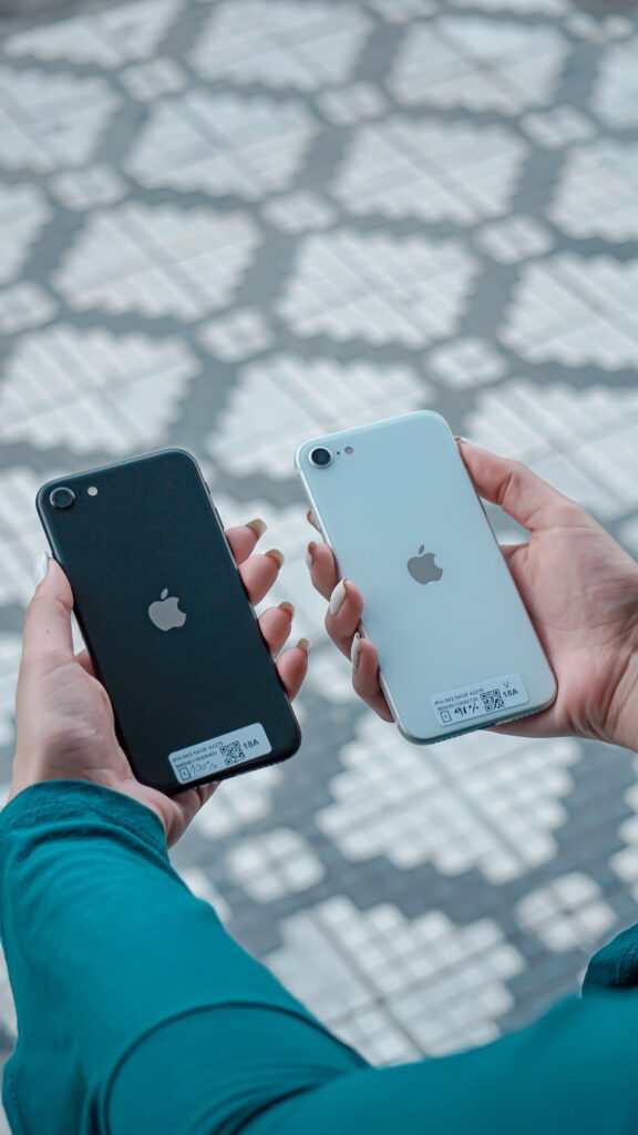 現在の画像: Hands holding two different colored smartphones on a textured background.