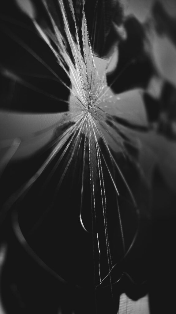 現在の画像: Intricate black and white close-up of cracked glass creating an abstract pattern.