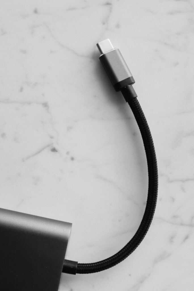 現在の画像: Minimalist black and white photograph of a USB-C cable on a marble background.
