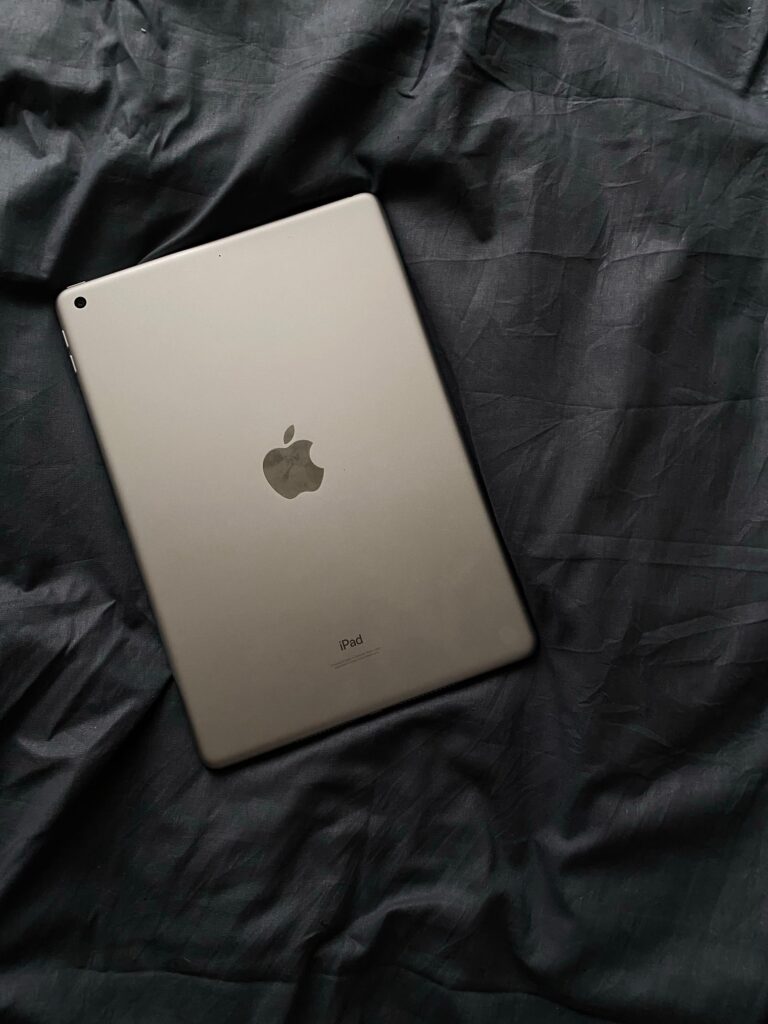 現在の画像: Minimalist shot of an Apple iPad on a crumpled dark fabric background.