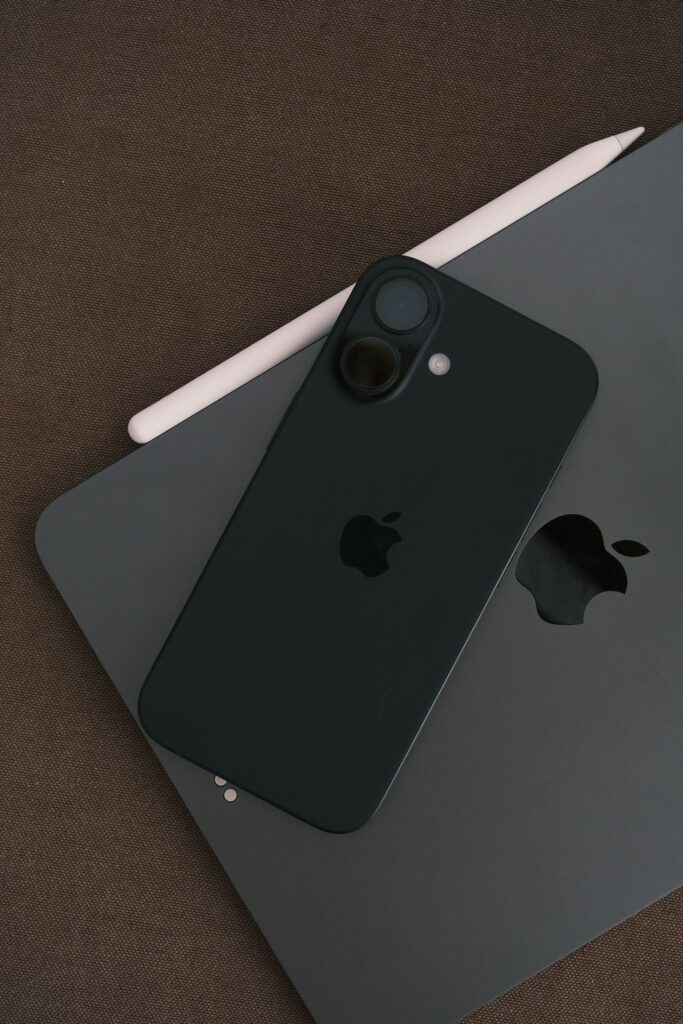 現在の画像: Modern black smartphone on laptop with a stylus in a minimalist setup.
