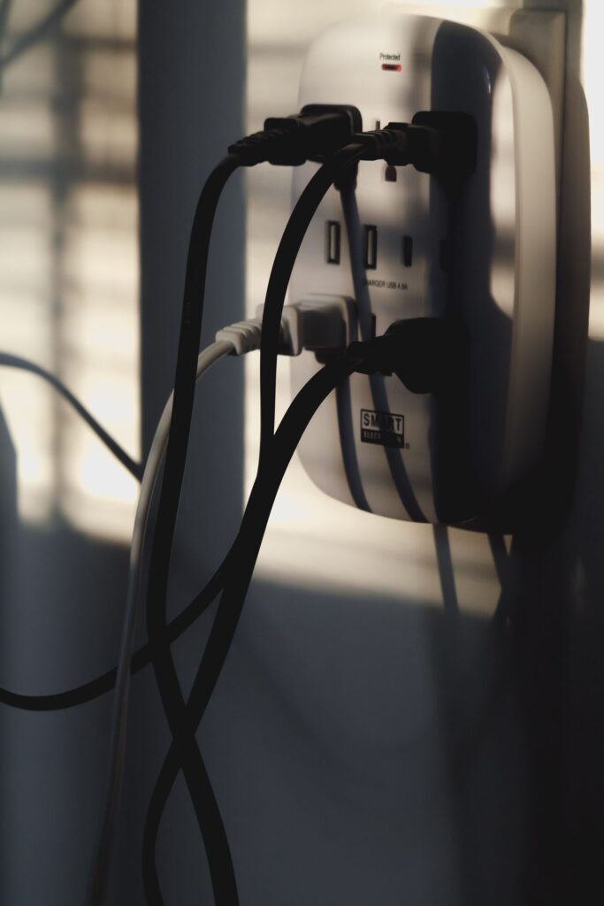 現在の画像: Multiple charging cables plugged into a wall outlet, showcasing energy connectivity.