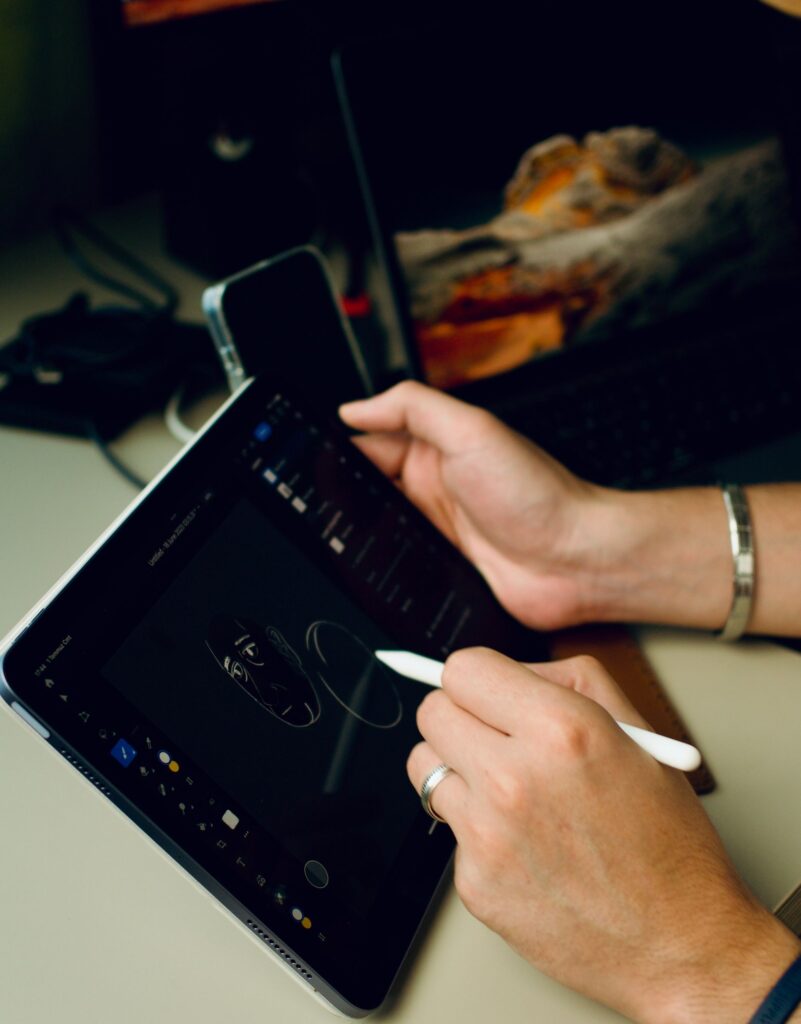 現在の画像: Person drawing digital art on a tablet indoors, showcasing technology and creativity.